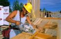 Construction worker using a handheld power saw to cut lumber.