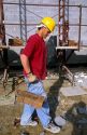 A mason assistant hod carrier  moving bricks with a carrier clamp.