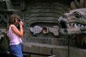 A female tourist taking a photograph of the pyramid serpent head at Teotihuacan, Mexico.