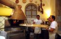 An Italian chef placing a pizza in a wood heated oven, Italy.