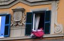 Bedding is aired at a window with blue shutters on an apartment in Lucca, Italy.