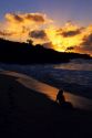 A woman silhouetted on the beach at sunset in Hawaii.