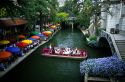 Visitors on a boat tour and people dining along the River Walk in San Antonio, Texas.