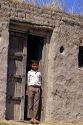 Boy standing at the door of a mud covered shack at a Plains village near Aurangabad, India.