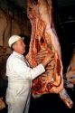 Meat inspector looking at a side of beef in a meat packing plant.
