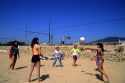 Teens play volleyball on the beach in Spain.