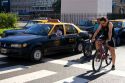 Bicyclists and taxis wait in traffic. Buenos Aires, Argentina.