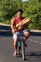 Tahitian man carrying baguettes while riding a bicycle on the island of Moorea.