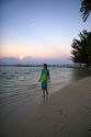 A woman walking on the beach at dusk on the island of Moorea. MR