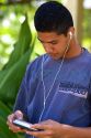 Teenage boy listening with head phones to a cd player on the island of Moorea.