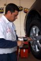 Installing tire on automobile. Mechanic uses impact air wrench.