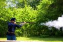 Civil war soldier reenactor and park ranger fires a musket at Shiloh National Park battlefield, Tennessee.