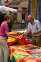A woman purchasing a table cloth at an open air market in the village of Ribeauville, Eastern France.