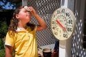 Nine year old girl wipes sweat from her forehead in 100 degree weather.