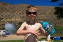 Five year old boy applying sunblock while at the beach. Sandy Point near Boise, Idaho. MR