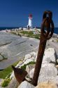 Large rusty anchor in front of a lighthouse at Peggy's Cove, Nova Scotia, Canada.