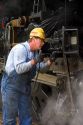 Brakeman greases bearings of historic Challenger locomotive steam engine.