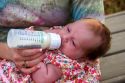 Mother bottle feeding her newborn baby daughter. MR