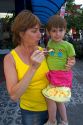 Mother and daughter eating a corn snack purchased from a street vendor in the Liberdade asian section of Sao Paulo, Brazil.
