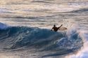 Surfing on waves at dusk in the pacific ocean off the island of Maui, Hawaii.