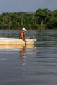 Brazilian man handline fishing in a small boat on the Arasa River in the Amazon jungle near Manaus, Brazil.