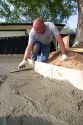 Worker leveling a newly poured concrete driveway in Boise, Idaho.