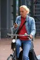 Woman using a cell phone while riding a bicycle in Amsterdam, Netherlands.