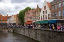 Storefronts and people along a canal in the city of Bruges in the province of West Flanders, Belgium.