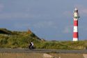 People ride bicycles past the Nieuwpoort Lighthouse at Nieuwpoort in the province of West Flanders, Belgium.