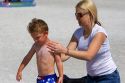 Mother applying sunscreen to her son on the beach at St. Petersburg, Florida. MR
