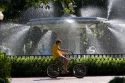 Bicyclist rides past a large water fountain in Forsyth Park in the historic district of Savannah, Georgia.
