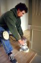 Construction worker using a power edge sander on new installation of a hardwood floor.