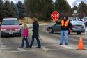 School crossing guard stops traffic to allow children and parents to cross the street in Boise, Idaho.