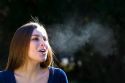 Young woman exhaling into cold outdoor air. MR