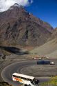 A bus and trucks drive on switchback roads in the Andes Mountain Range in Chile.