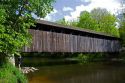 Whites Bridge, a brown truss covered bridge spanning the Flat River in Keene Township, Michigan.