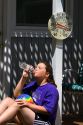 11 year old girl drinking water below a thermometer reading 100 degrees fahrenheit on a hot summer day in Boise, Idaho. MR