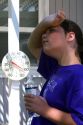 11 year old girl drinking water below a thermometer reading 100 degrees fahrenheit on a hot summer day in Boise, Idaho. MR