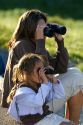 Hispanic mother and daughter viewing wildlife with binoculars in Yellowstone National Park, Wyoming. MR