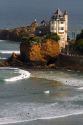 Surfing Cote de Basque below a castle in the Bay of Biscay at the town of Biarritz, Pyrenees Atlantiques, French Basque Country, Southwest France.