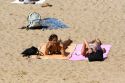Women sunbathe and talk on cell phones at the beach in the seaside town of Biarritz, Pyrenees Atlantiques, French Basque Country, Southwest France.