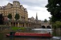 A narrowboat on the River Avon in front of the Pulteney Bridge and Abbey Hotel in the city of Bath, Somerset, England.