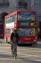 Bicyclist and a double decker bus in the city of London, England.