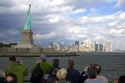 Tourists view the Statue of Liberty and Lower Manhattan from New York Harbor, New York, USA.