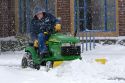 John Deere riding lawn mower fitted with a snow plow removing snow from a parking lot in Boise, Idaho, USA.