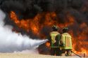 Firefighters using fire retardant foam to put out a jet fuel fire at an airport training facility in Boise, Idaho, USA.
