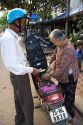 Vietnamese man purchasing one liter of gasoline from a woman on the street in Hue, Vietnam.