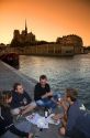 Parisiens picnicing along the River Seine at sunset in Paris, France.