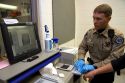 Jailer fingerprinting a suspect using a modern scanner during the booking process at a jail.