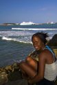 Costa Rican afro-caribbean woman on the beach with the  AIDAaura cruise ship docked in the background at Puerto Limon, Costa Rica.